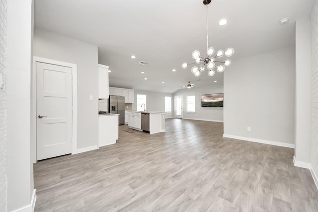 unfurnished living room with recessed lighting, ceiling fan with notable chandelier, light wood-type flooring, and baseboards