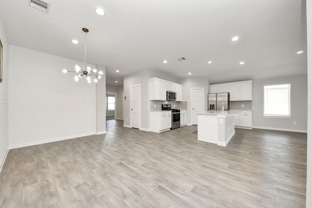 kitchen featuring light wood finished floors, visible vents, open floor plan, light countertops, and stainless steel appliances