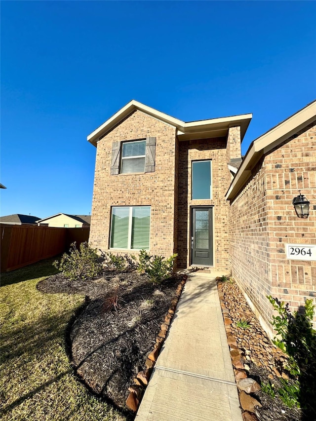 property entrance featuring brick siding and fence