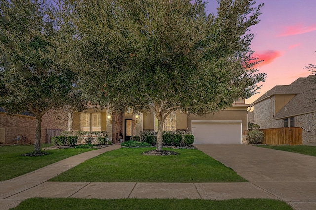 view of front facade with stucco siding, concrete driveway, a front lawn, and fence