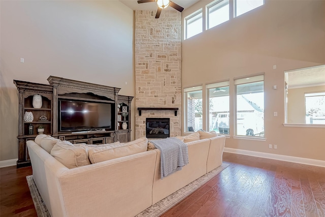 living room with baseboards, a ceiling fan, wood finished floors, and a fireplace