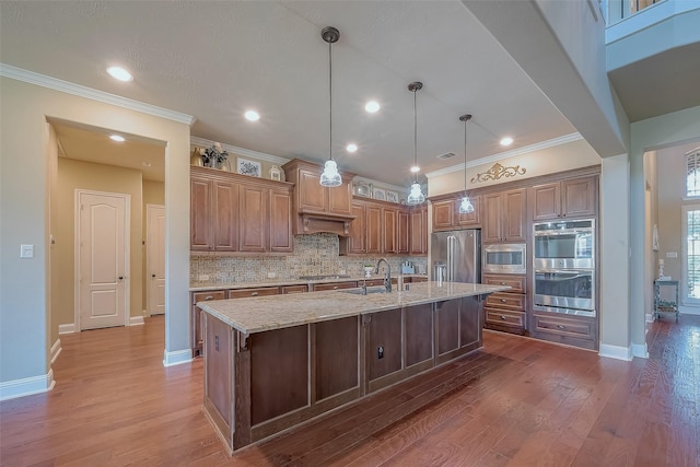 kitchen featuring a sink, stainless steel appliances, wood finished floors, and decorative backsplash