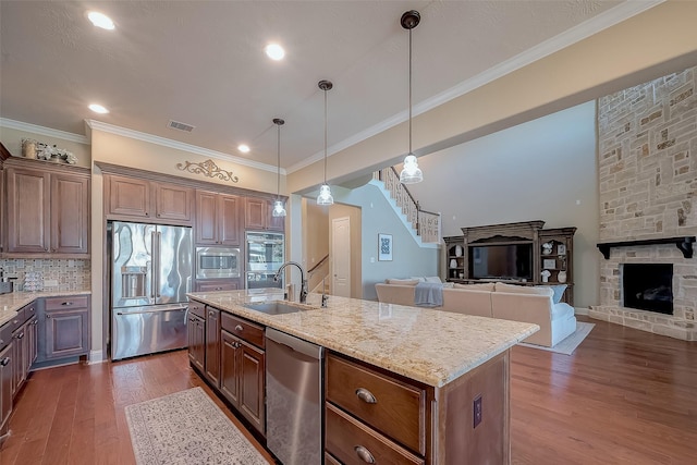 kitchen with visible vents, dark wood-type flooring, a sink, light stone counters, and stainless steel appliances