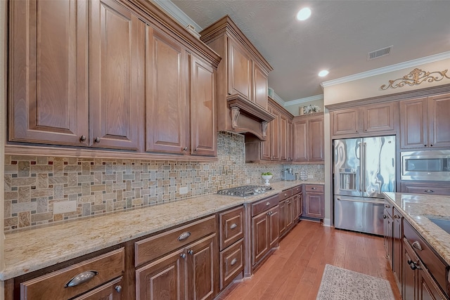 kitchen with visible vents, crown molding, decorative backsplash, light wood-style flooring, and stainless steel appliances