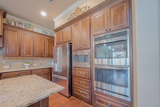 kitchen with crown molding, decorative backsplash, light wood-style flooring, appliances with stainless steel finishes, and brown cabinetry