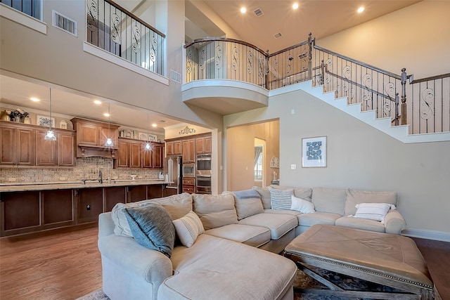 living area featuring visible vents, baseboards, light wood-style floors, and stairs