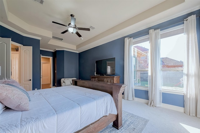 carpeted bedroom with baseboards, visible vents, ceiling fan, ornamental molding, and a raised ceiling