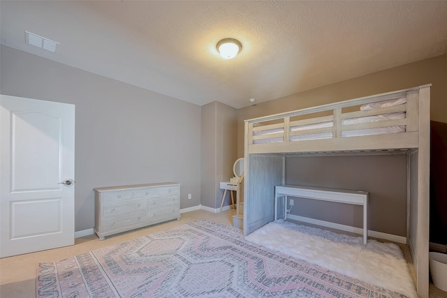 unfurnished bedroom with visible vents, a textured ceiling, carpet, and baseboards