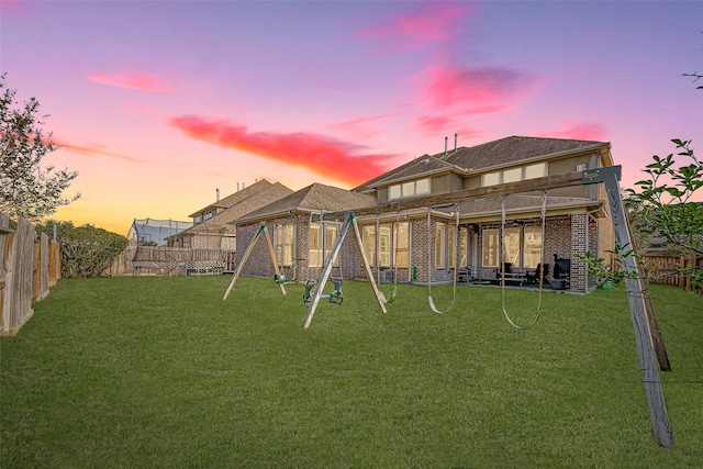 yard at dusk featuring a fenced backyard and a playground