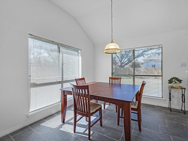 dining area featuring vaulted ceiling, dark tile patterned floors, and baseboards