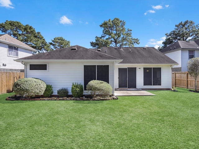 back of house featuring a patio area, a lawn, a shingled roof, and a fenced backyard