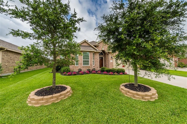 view of front of property featuring brick siding, an attached garage, and a front yard