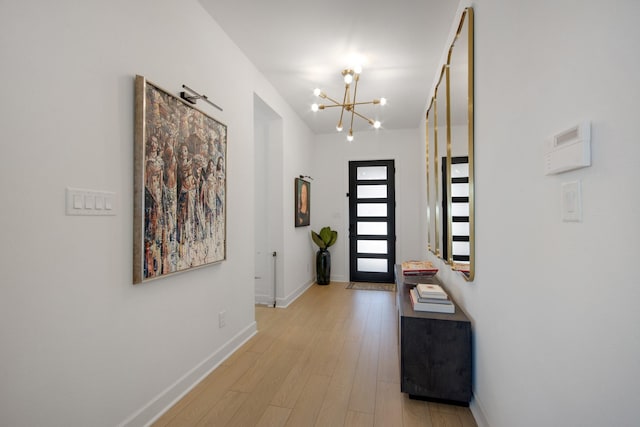 foyer entrance featuring baseboards, an inviting chandelier, and wood finished floors