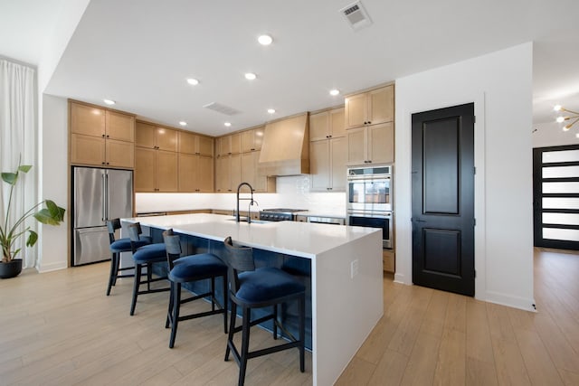 kitchen featuring visible vents, light brown cabinets, stainless steel appliances, light wood finished floors, and custom exhaust hood