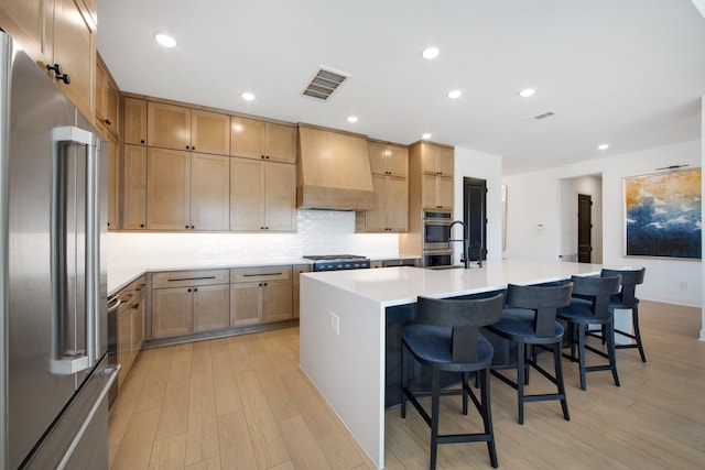 kitchen with visible vents, custom range hood, backsplash, light wood-style floors, and appliances with stainless steel finishes