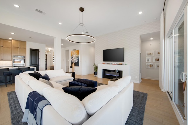 living room featuring wallpapered walls, recessed lighting, visible vents, and an accent wall