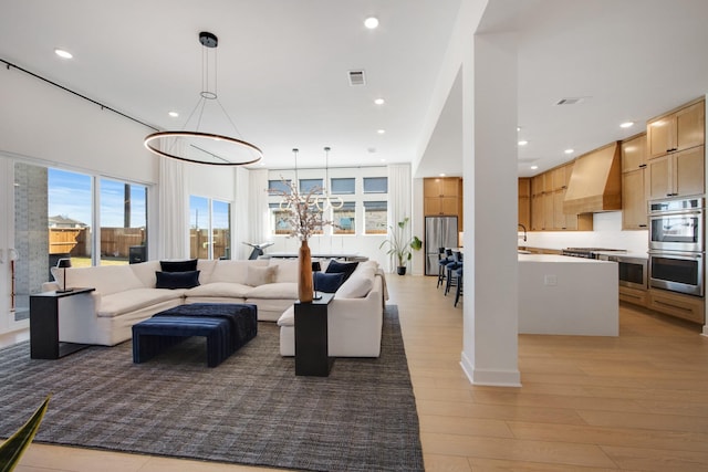 living room with recessed lighting, light wood-style floors, and visible vents