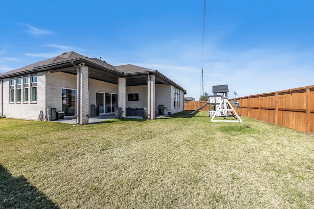 back of property featuring a yard, a patio, a fenced backyard, and a playground