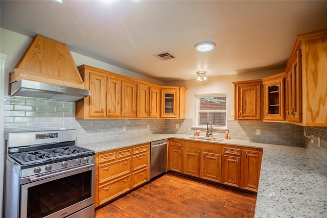 kitchen with visible vents, a sink, appliances with stainless steel finishes, light wood finished floors, and light stone countertops