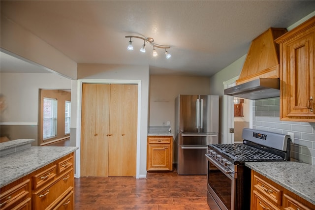 kitchen with brown cabinets, stainless steel appliances, decorative backsplash, custom exhaust hood, and dark wood-style flooring