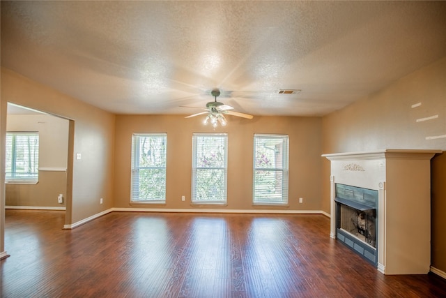 unfurnished living room featuring visible vents, a textured ceiling, dark wood-style floors, baseboards, and a tile fireplace