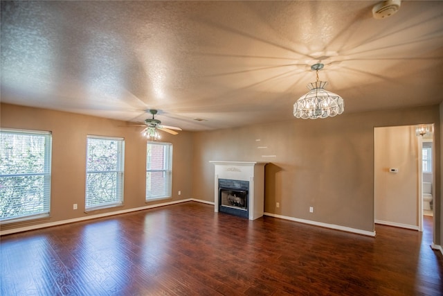 unfurnished living room featuring baseboards, a textured ceiling, dark wood-style floors, and a fireplace