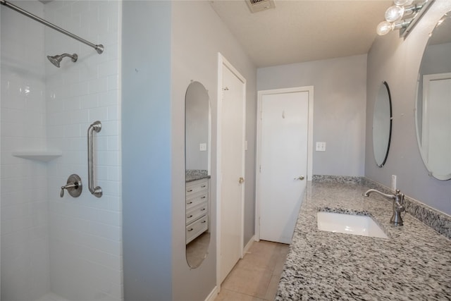 full bath with a tile shower, tile patterned flooring, and vanity