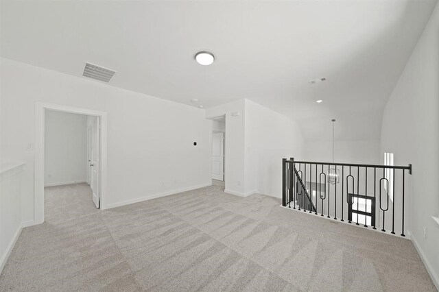 carpeted empty room featuring vaulted ceiling, baseboards, and visible vents