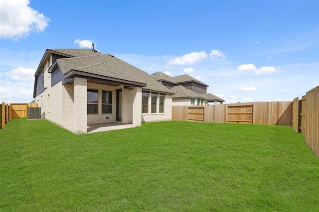 rear view of house with brick siding, a fenced backyard, a lawn, and a patio area