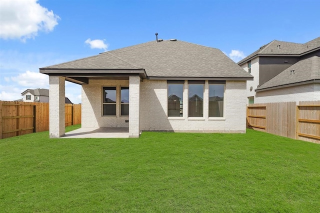 rear view of house featuring a fenced backyard, a yard, brick siding, and a patio