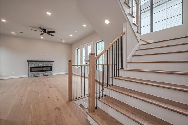 staircase featuring visible vents, wood finished floors, recessed lighting, a fireplace, and baseboards