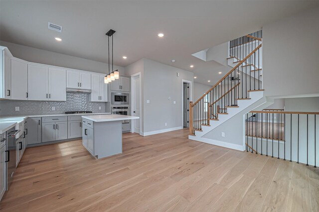 kitchen featuring visible vents, backsplash, a center island, light wood-style flooring, and stainless steel appliances