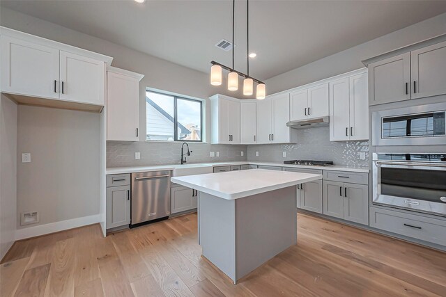 kitchen with visible vents, under cabinet range hood, stainless steel appliances, light wood-style floors, and light countertops