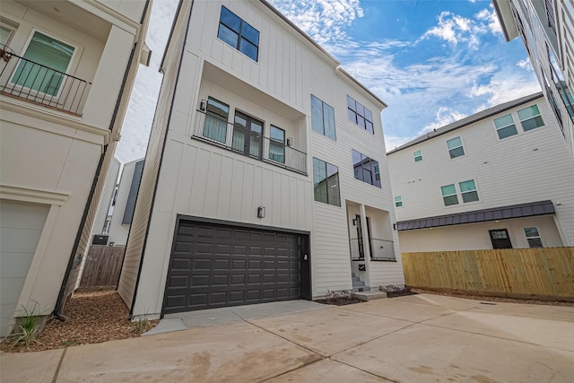 exterior space with an attached garage, fence, board and batten siding, and driveway