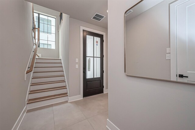 tiled foyer entrance featuring stairs, baseboards, and visible vents