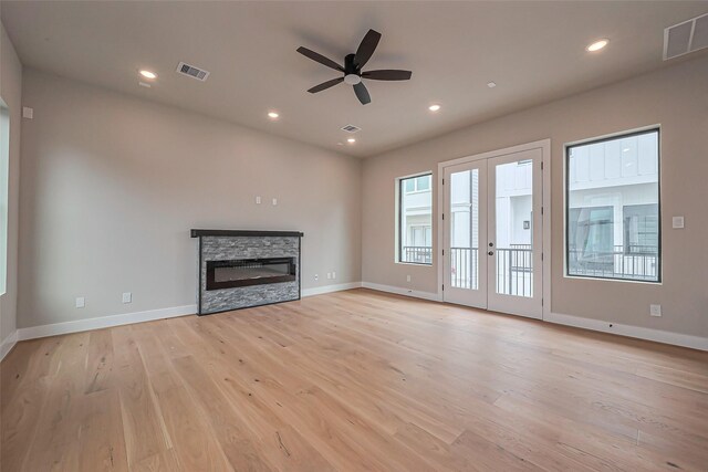 unfurnished living room with visible vents, light wood-style flooring, a fireplace, and french doors