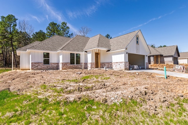 modern farmhouse style home with brick siding, board and batten siding, concrete driveway, roof with shingles, and a garage