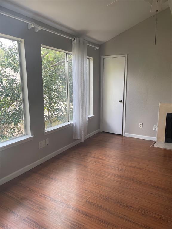 12400 Overbrook Ln Unit 45C, Houston, TX 77077 - unfurnished living room with wood finished floors, healthy amount of natural light, and vaulted ceiling