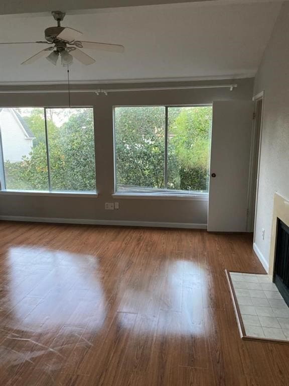 12400 Overbrook Ln Unit 45C, Houston, TX 77077 - unfurnished living room with a tiled fireplace, a ceiling fan, wood finished floors, and baseboards