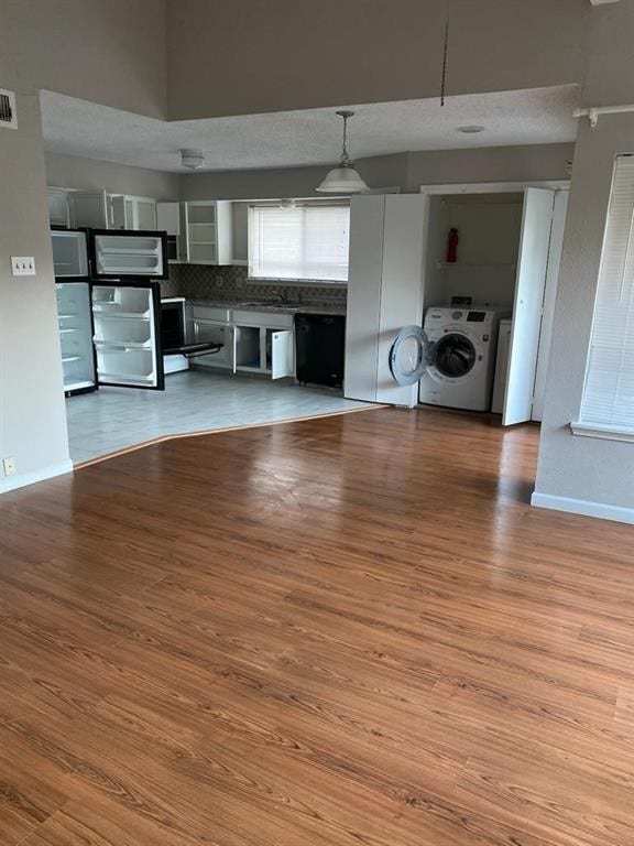 12400 Overbrook Ln Unit 45C, Houston, TX 77077 - unfurnished living room featuring washer / clothes dryer, wood finished floors, and baseboards
