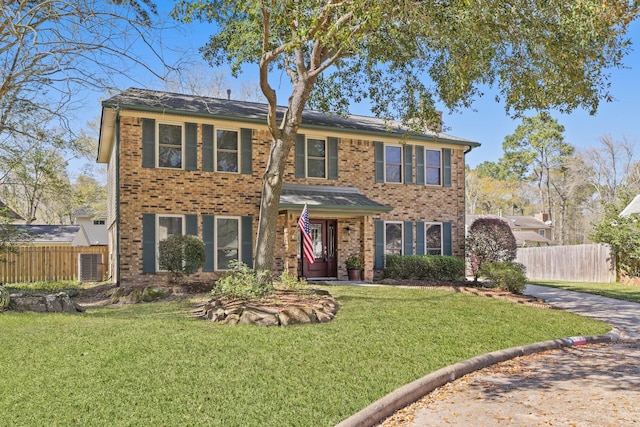 colonial house featuring brick siding, a front lawn, and fence