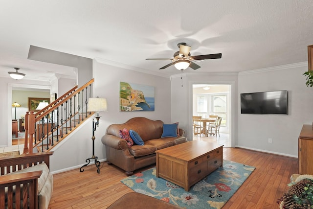 living room with stairway, baseboards, ornamental molding, and light wood finished floors