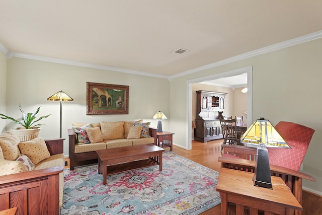 living room with visible vents, light wood-type flooring, baseboards, and ornamental molding