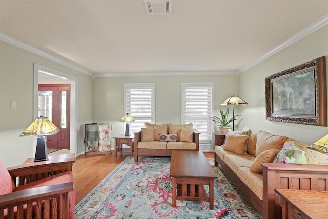 living area featuring visible vents, wood finished floors, and ornamental molding