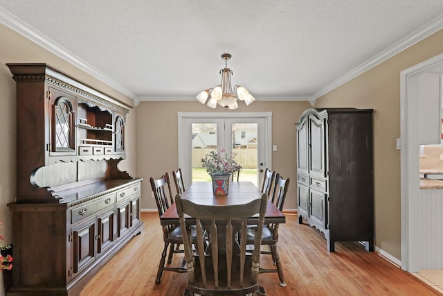 dining space with a notable chandelier, baseboards, light wood-style floors, and crown molding