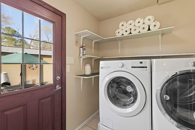 laundry room with washer and dryer, a textured ceiling, light tile patterned floors, baseboards, and laundry area