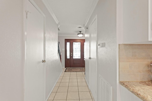 entryway with crown molding, light tile patterned floors, a textured wall, and visible vents