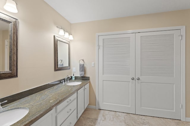 bathroom featuring double vanity, baseboards, and a sink