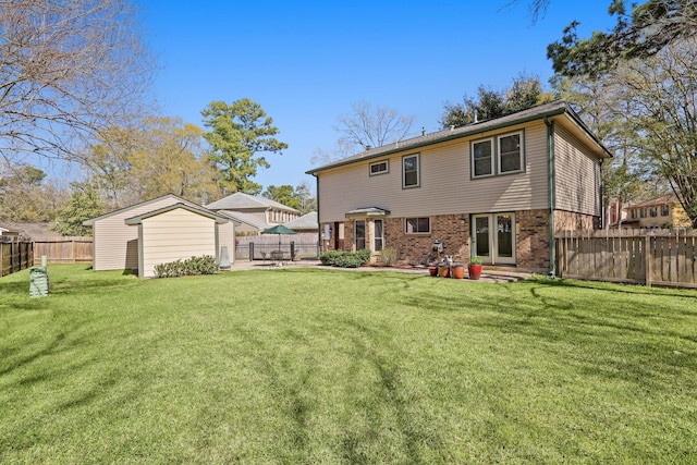 back of house with an outbuilding, a lawn, brick siding, and a fenced backyard