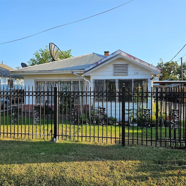 view of front facade with metal roof, a fenced front yard, and a front yard